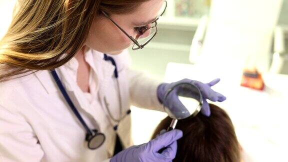 毛发学家用放大镜检查病人头上的头发状况