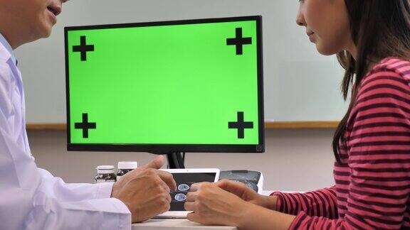 医生用绿色屏幕的电脑显示器与病人交谈