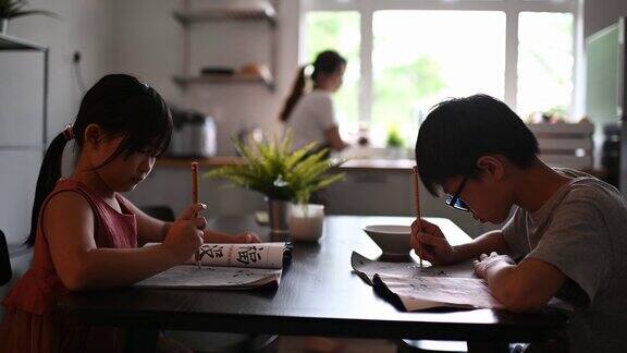 2个孩子在家学习写中国书法在餐厅