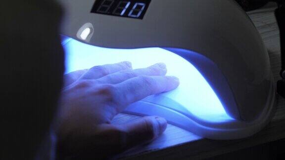 女性指甲在蓝光紫外线灯下美甲现代指甲油在led灯下的固化、干燥和固定技术美容院程序美甲沙龙服务概念在线美甲培训