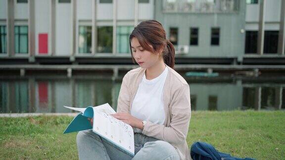 亚洲女子大学的学生坐在校园草地上看快乐和在公园看书