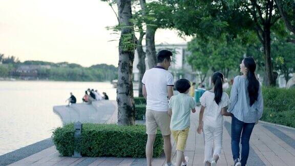 黄昏时分亚洲一家四口在海滨散步