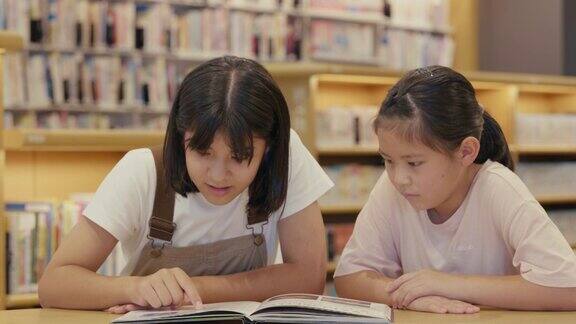 MS两个年轻女孩一起在图书馆放松