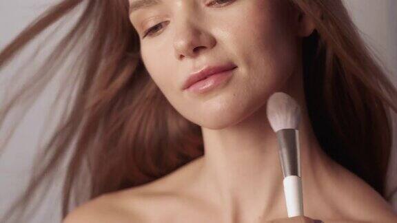 美女化妆师用化妆刷抚摸脸部肌肤