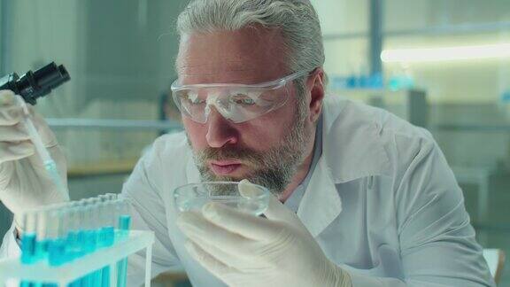 高级化学家在实验室的试管中注入蓝色化学物质