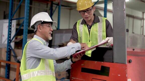 在工厂使用叉车搬运货物完成后亚洲华人仓库工人将文件交给主管签字