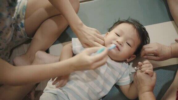 父母正在用牙刷帮儿子刷牙