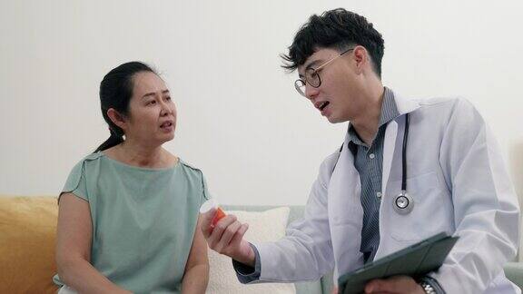 年轻的亚洲男性医生向老年病人解释药物