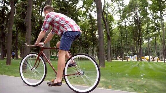 在公园路上骑车的运动男年轻英俊的男人在户外骑着一辆老式自行车健康积极的生活方式侧视图关闭慢动作低角度视图