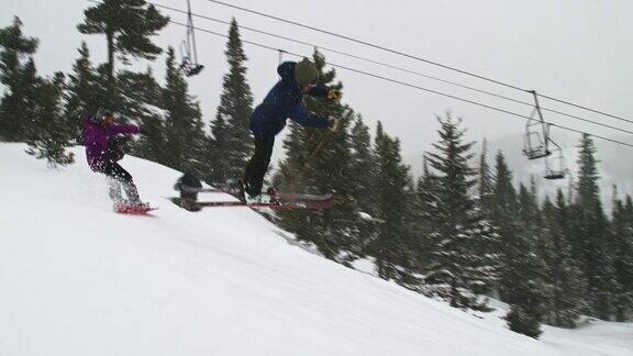 在科罗拉多州博尔德附近的埃尔多拉滑雪度假村滑雪者在跳跃中完成“开关左Rodeo540双抓”技巧同时滑雪者用摄像机从侧面拍摄森林和滑雪缆车的背景