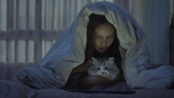 年轻女子亲吻猫并在床上使用药片