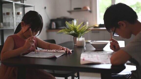 2个孩子在家学习写中国书法在餐厅