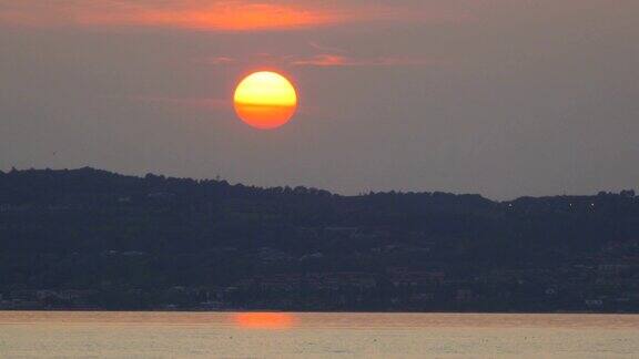 加尔达湖和山丘上的日落橙色的太阳