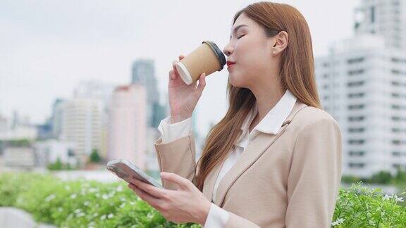 一位身着商务休闲装的女士正在享受茶点和休闲时光手里拿着智能手机享受着咖啡休息时间庆祝现代专业人士在快节奏的工作环境中找到快乐和放松的能力