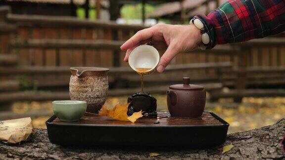 一位茶艺大师将普洱茶从碗里倒在青蛙茶雕像上户外茶道