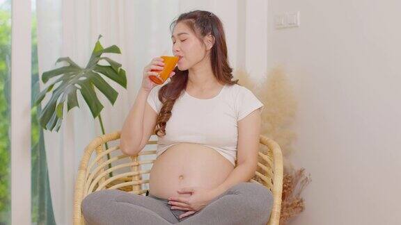 健康的亚洲孕妇饮用胡萝卜汁维生素A和高维生素C和K天然胡萝卜新鲜汁怀孕健康概念