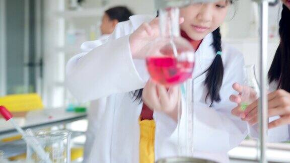 小学生科学实验学校化学实验室的STEM教育小女孩混合和滴化学物质在烧杯