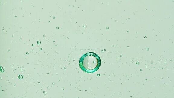 移动气泡的慢动作镜头在绿色背景上水中各种气泡上升的微距镜头液体奶油凝胶透明化妆品样品纹理泡沫