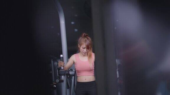 穿着粉色衣服的健康亚洲女性在机器上锻炼腹肌