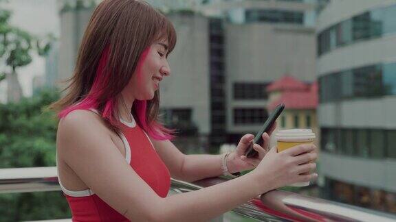 微笑的年轻女子在城市里用智能手机看风景