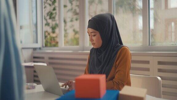 快乐的女企业家戴着头巾用笔记本电脑和客户交流做生意