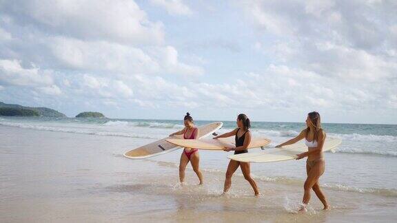 一群女子抱着冲浪板在沙滩上散步