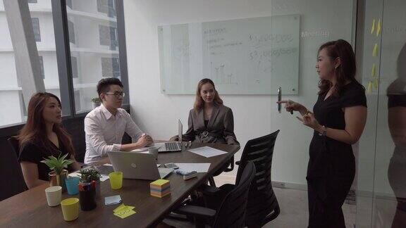 在办公室的会议室里一位年轻的亚洲华人高管正在主持一场会议