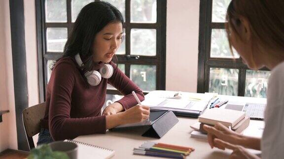 迷人的亚洲大学生使用笔记本电脑和平板电脑与一群朋友一起学习英语课堂社交媒体和教育理念