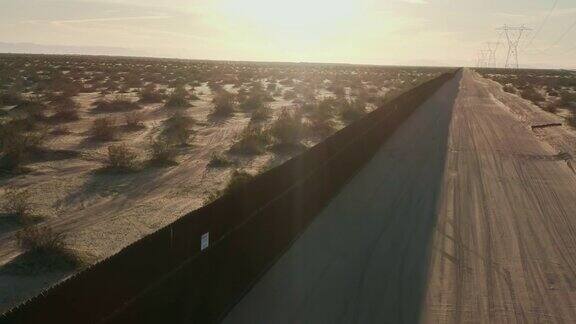 一个阳光明媚的下午在加州墨西哥沙漠中远处的群山为背景一条与墨西哥和美国之间的钢条边境墙平行的土路