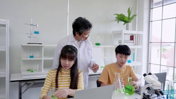 在课堂上可爱的亚洲人在试管里做着混合颜色的科学实验在学校实验室学习实验