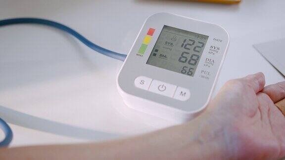 老年妇女在家用医疗器械手检查血压和心率