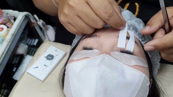 一位化妆师正在给一位年轻女子画睫毛
