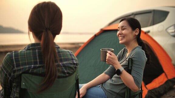两个露营的女人喝着啤酒享受日落看着美丽的山