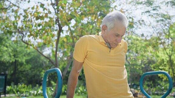 在早晨的阳光下一名印度老年男子正在休闲公园的露天健身房锻炼
