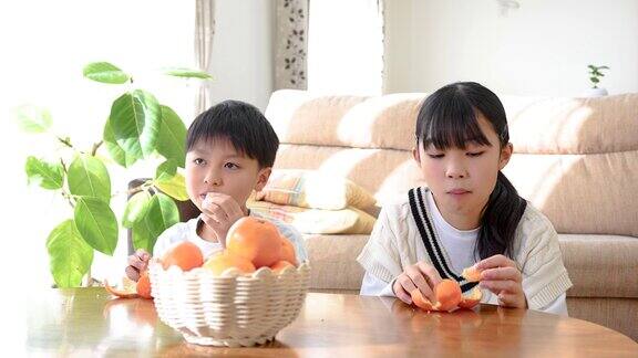 一个亚洲小孩在客厅的小餐桌上吃桔子