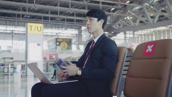 在机场用笔记本电脑工作的亚洲商人