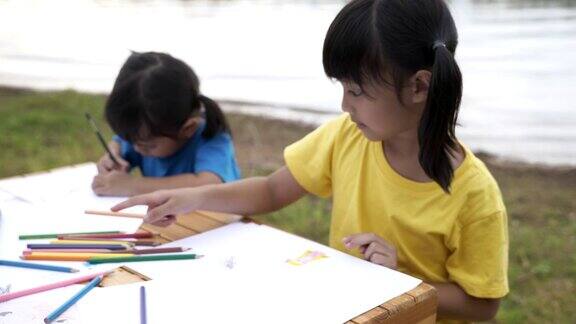 两姐妹用彩色铅笔在纸上画漫画