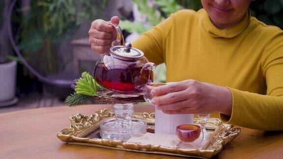 女子将茶从玻璃壶倒入杯中茶道概念