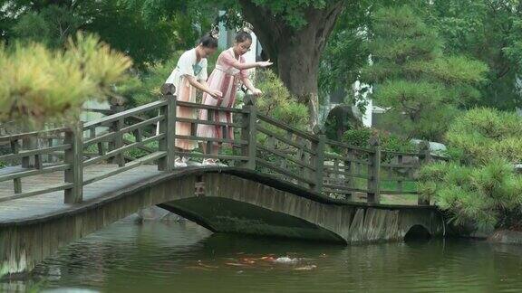 女孩们穿着汉服在公园喂锦鲤