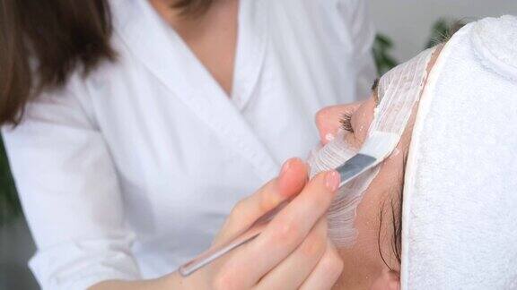 在美容院用粘土面膜护理一位女士的脸美容和水疗