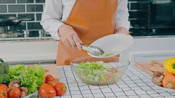 一名素食妇女在厨房做饭时用碗搅拌蔬菜沙拉