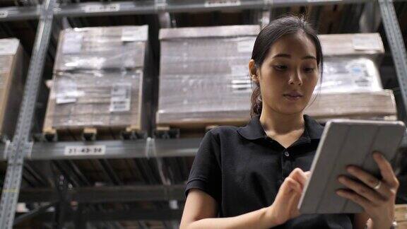 亚洲女工人在仓库用平板电脑检查物资