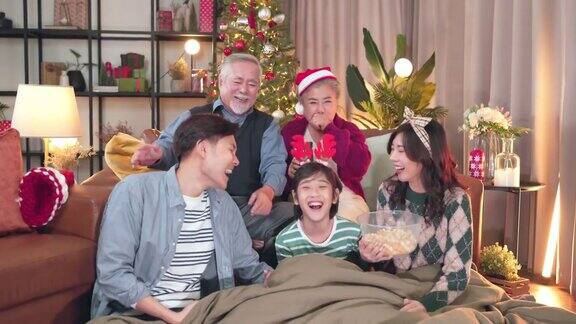 幸福亚洲家庭在家里一起度过欢乐的节日时刻多代家庭祖父母、父母和孩子在圣诞节期间在家一起看喜剧电影