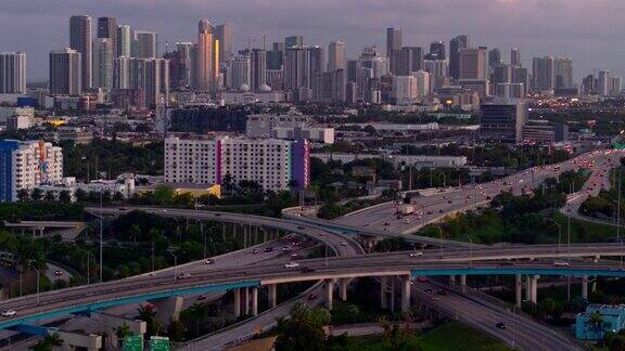 鸟瞰图迈阿密设计区和遥远的迈阿密市中心上空的大高架枢纽在北迈阿密佛罗里达州在晚上无人机拍摄的b-roll镜头和下降的摄像机动作