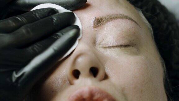 美容师在为一位女士清洁微叶片手术后的眉毛
