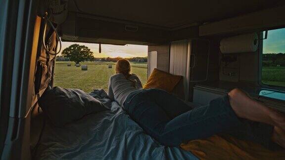 在日落时分DL女士从停在草地上的露营车的小木屋里欣赏风景