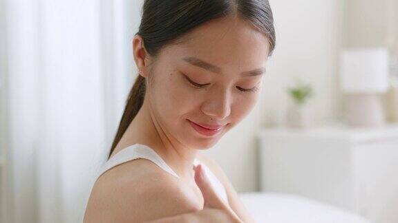 年轻的亚洲美女使用身体乳液和护肤霜亚洲美容皮肤