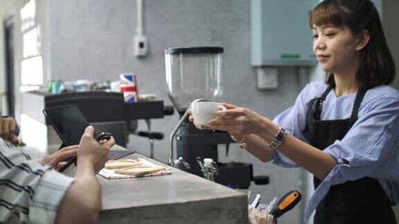 微笑的咖啡师为她的客户服务咖啡