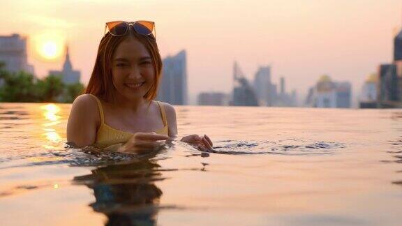 放松夏天休闲休闲亚洲女性女性在泳装上凉爽的藤条泳池长椅上躺在游泳池附近无边泳池边在建筑物的屋顶上夏天旅游度假日光浴