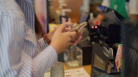 年轻女性在咖啡店用非接触式支付方式付款